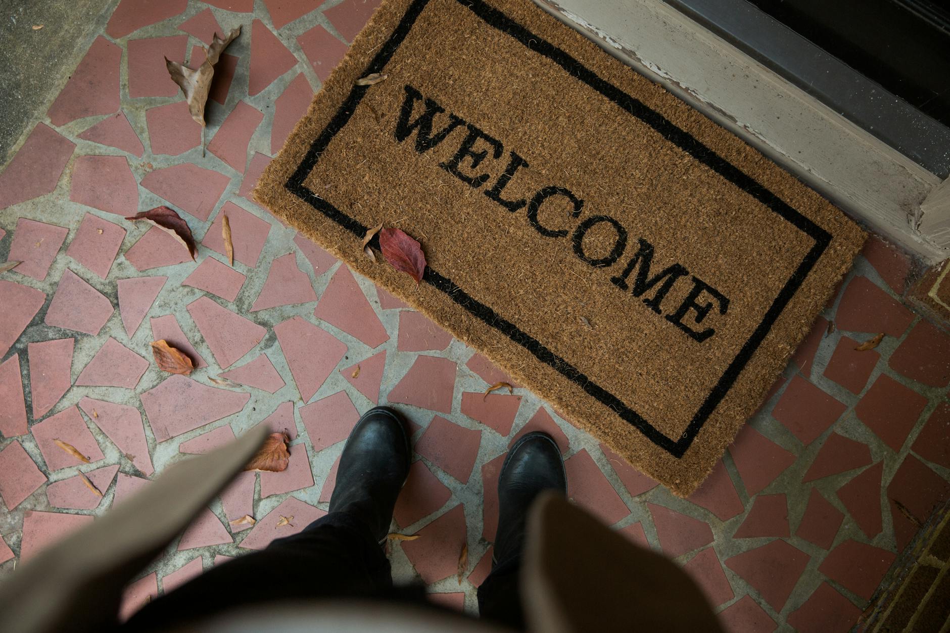 person wearing boots standing near a doormat